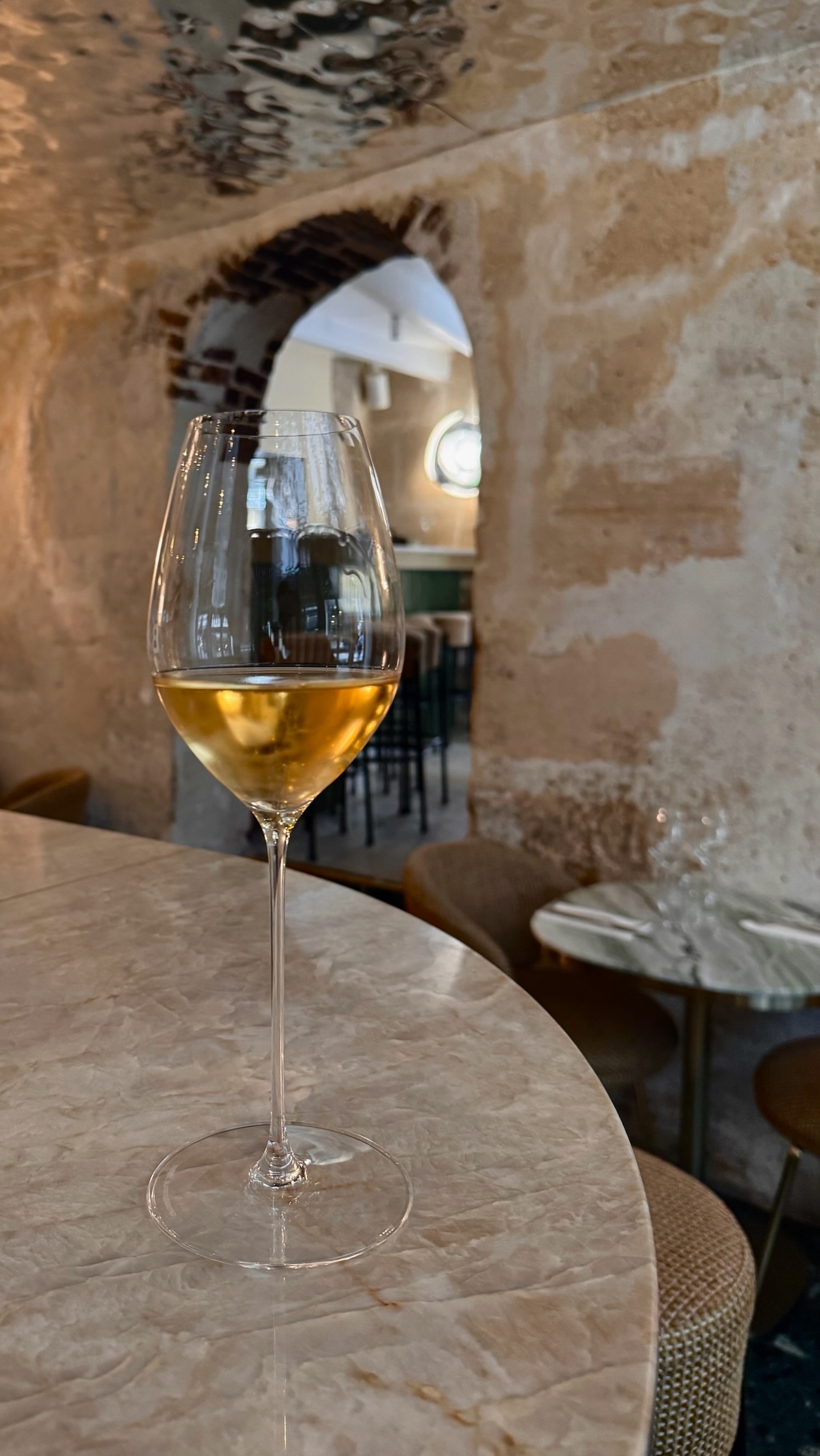 A glass of white wine on a marble bar in a stone-arched cave